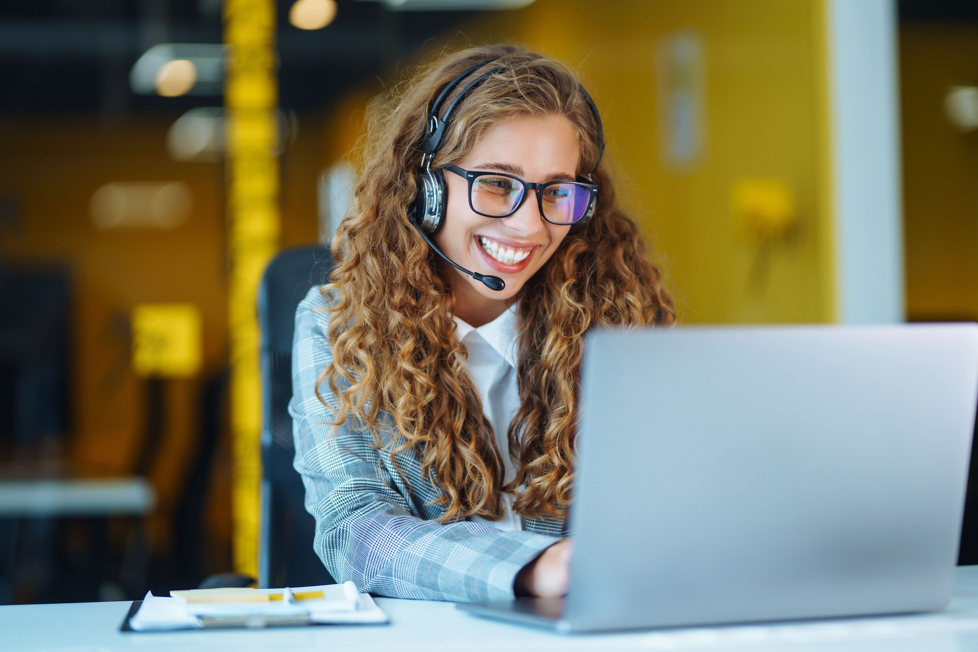 Female customer service representative in a headset is consulting clients online.